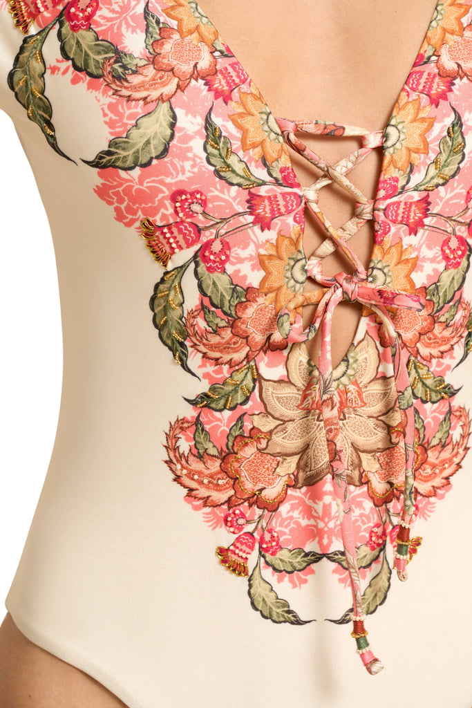 A close up look at the pattern of the Spirit Plunged One Piece Swimwear, with a plunge neckline, lace up cross tie details at the front and a moderate bottom coverage, in beige or nude color, with delicate rose colors, intricate flower inspired style pattern. 